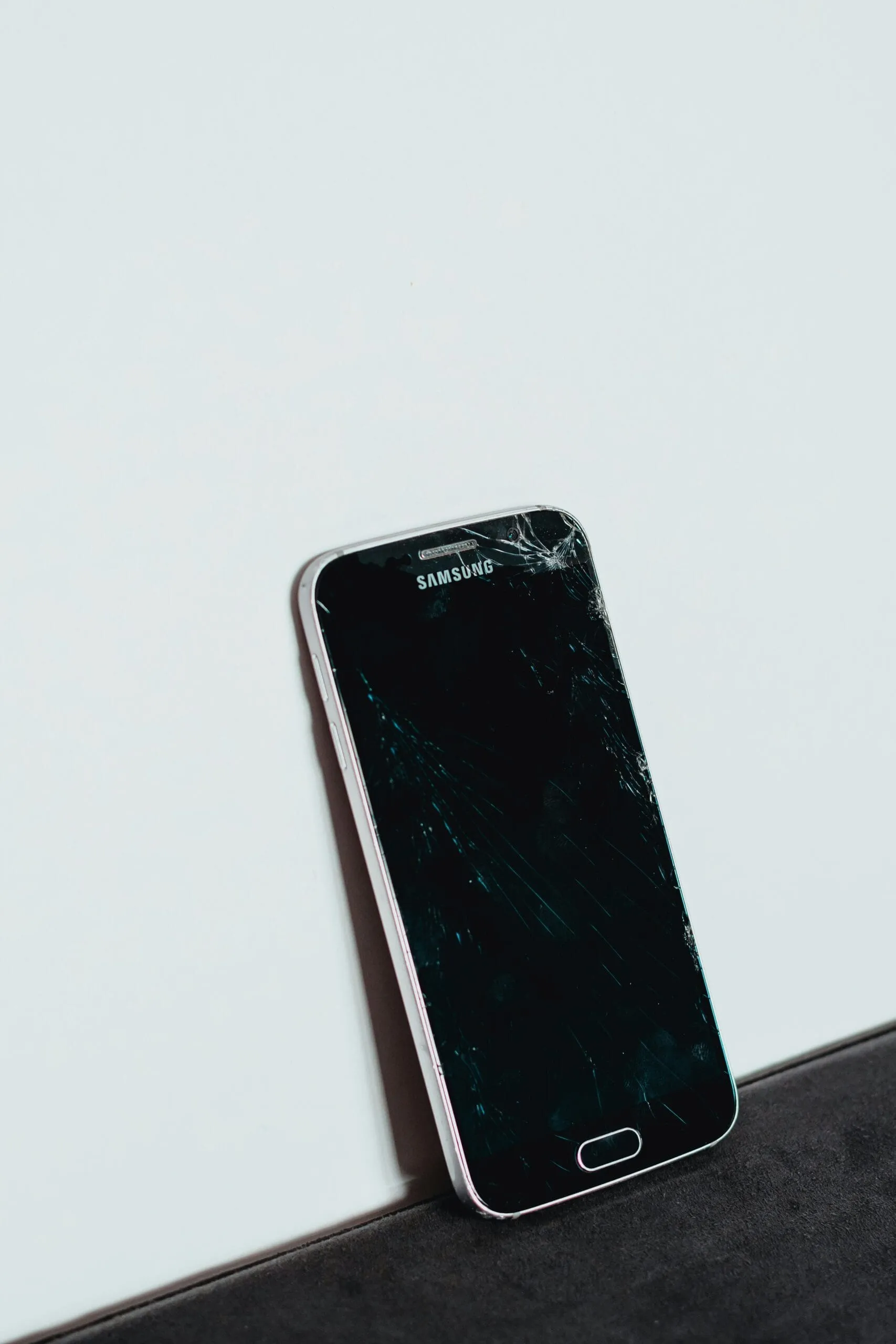 Celular Samsung com vidro trincado apoiado em uma superfície